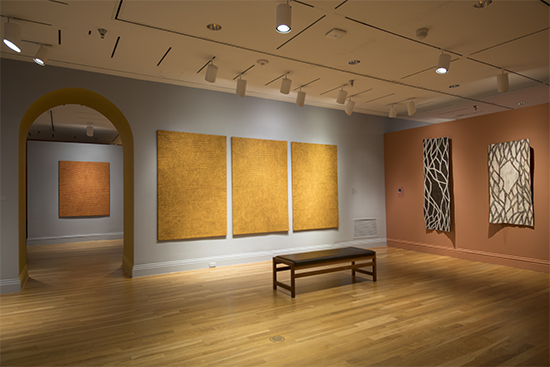 Showing, on the left, four synthetic polymer paint on canvas works by Yukultji Napangati and, on the right, two bark paintings by Nonggirrnga Marawili. (Photo by Lee Stalsworth)