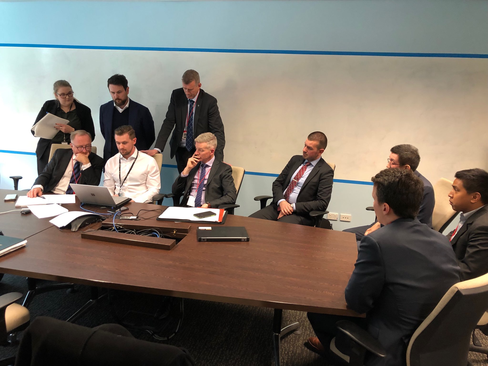 ABC lawyers and AFP officers hover over a computer as they work out what comes within the terms of the warrant. At the end of the table, on the right, are the AFP digital forensics people. (photograph by John Lyons)