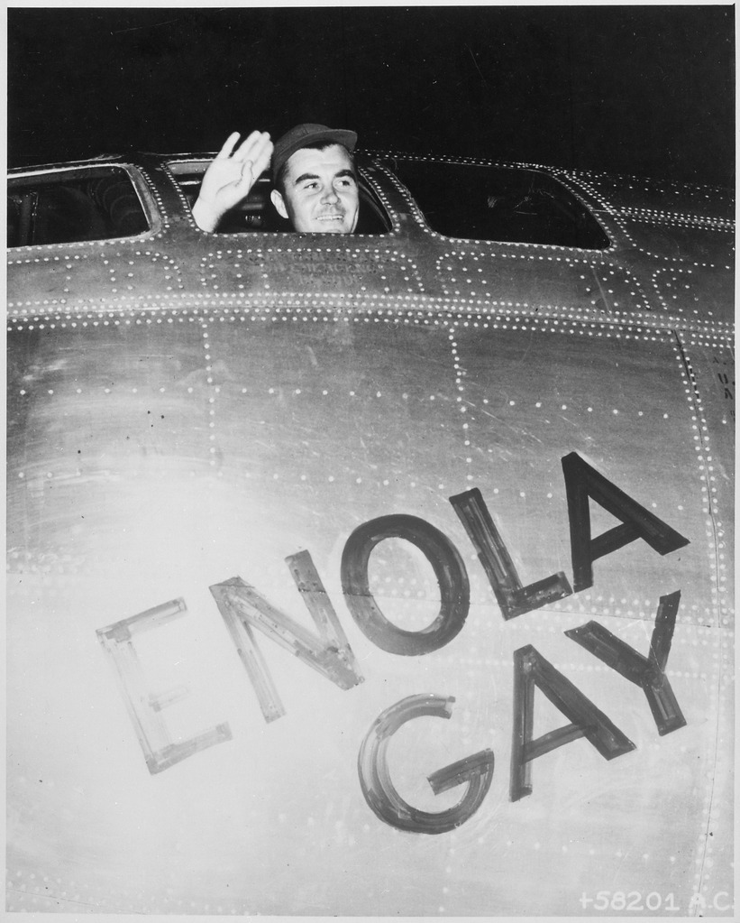 Colonel Paul W. Tibbets, Jr., pilot of the ENOLA GAY, the plane that dropped the atomic bomb on Hiroshima, waves from his cockpit before the takeoff, 6 August 1945 (photo from the U.S. National Archives and Records Administration via Wikimedia Commons)